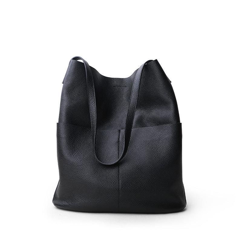Black cowhide leather tote bag with two front pockets and minimalist design on white background