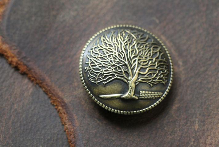Close-up of embossed bronze tree button on brown leather journal cover