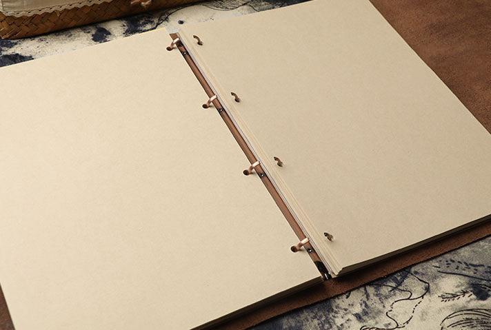 Open vintage leather sketchbook with blank kraft pages on a rustic surface