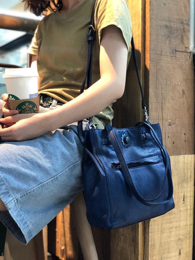 Woman with blue leather shoulder bag, casual outfit, sitting in cafe