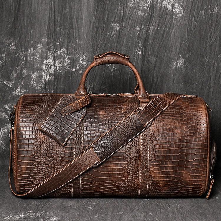 Brown crocodile-embossed full grain leather duffle bag with shoulder strap and tag