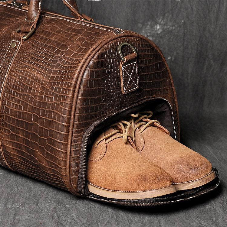 Brown full grain leather duffle bag with shoe compartment, textured cowhide pattern.