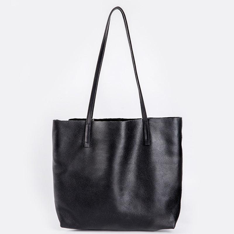 Large black full-grain leather tote bag with long handles on white background