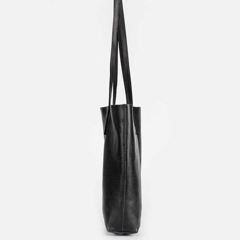 Side view of large black full-grain leather tote bag with long handles