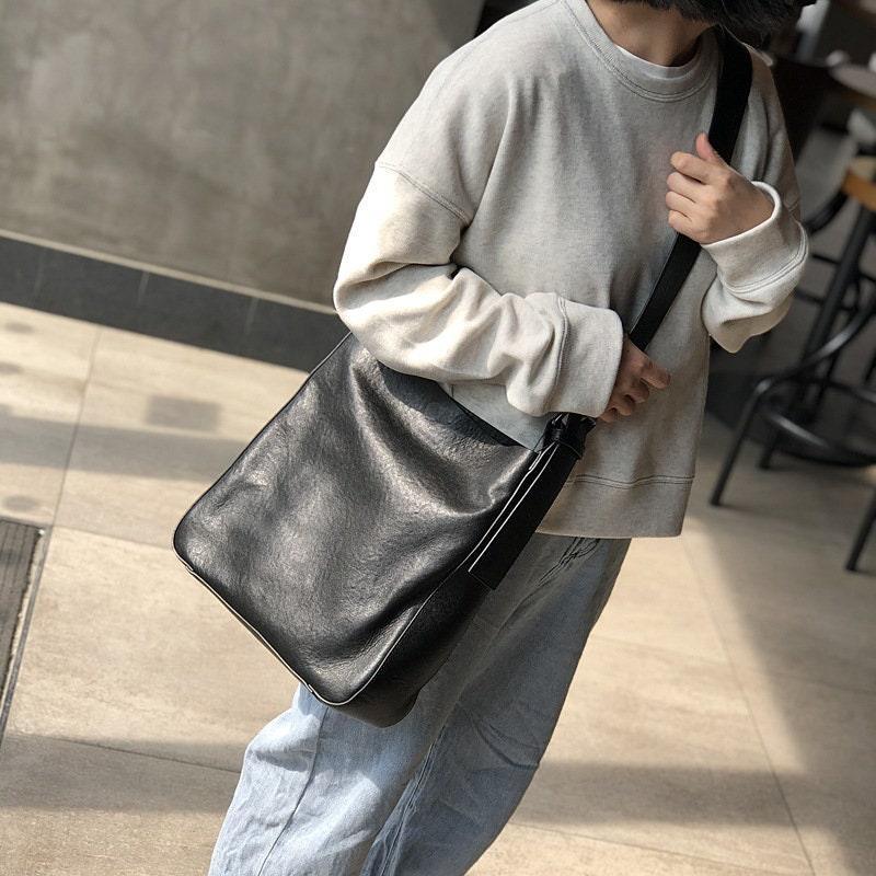 Woman wearing a black full grain leather shoulder bag with wide strap, casual outfit