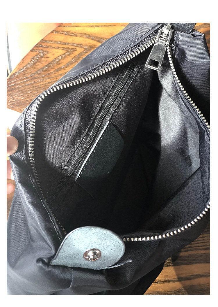 Interior of a full grain leather shoulder bag with zipper pocket and snap button, on wooden table