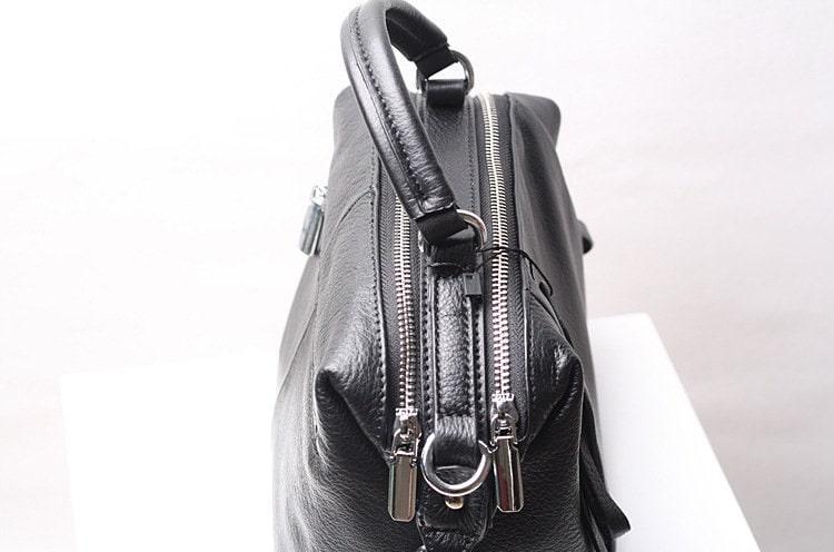 Black genuine leather handbag with dual zippers and top handle on white background