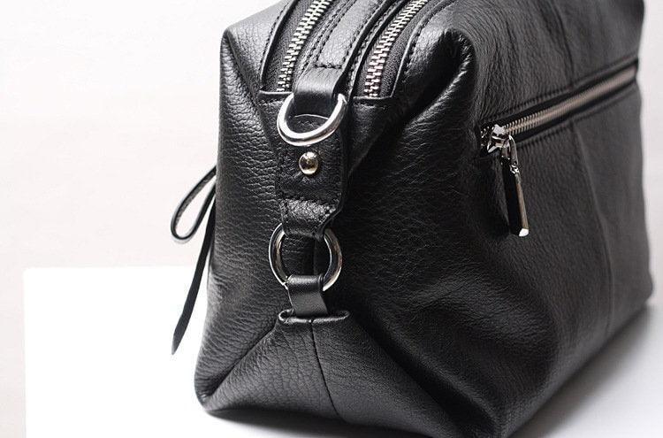 Black genuine leather handbag with zip closure and silver hardware on a white surface