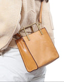 Tan Italian leather shoulder bag with gold handle, worn crossbody by a woman in beige top