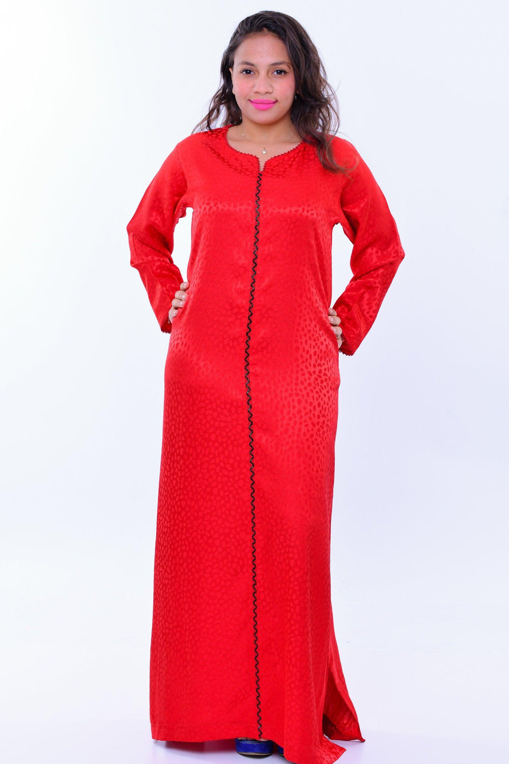 Woman wearing a bright red handcrafted silk kaftan dress with long sleeves and black trim