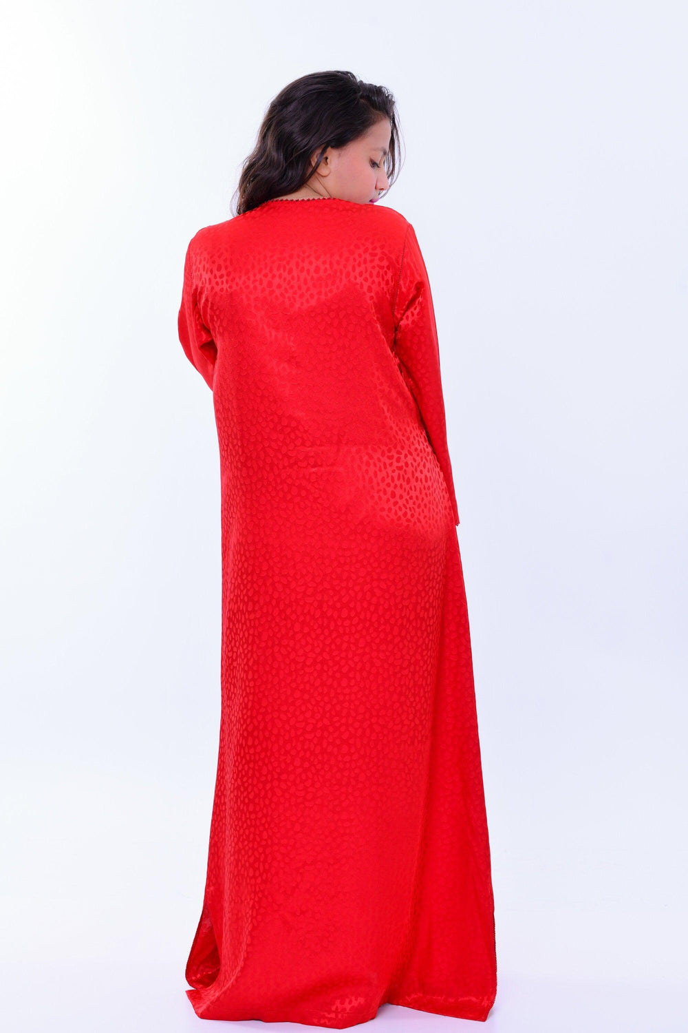 Woman wearing long red boho silk kaftan dress with subtle pattern and wide sleeves