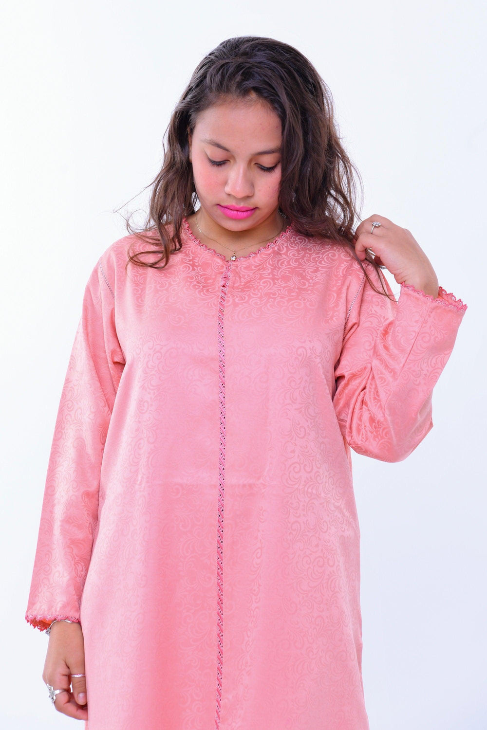 Woman wearing a handcrafted pink kaftan maxi dress with subtle patterns against white background