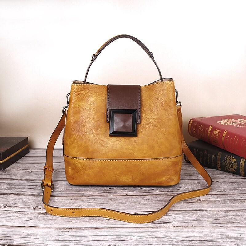 Handcrafted tan leather shoulder bag with brown flap, crossbody strap, and decorative buckle