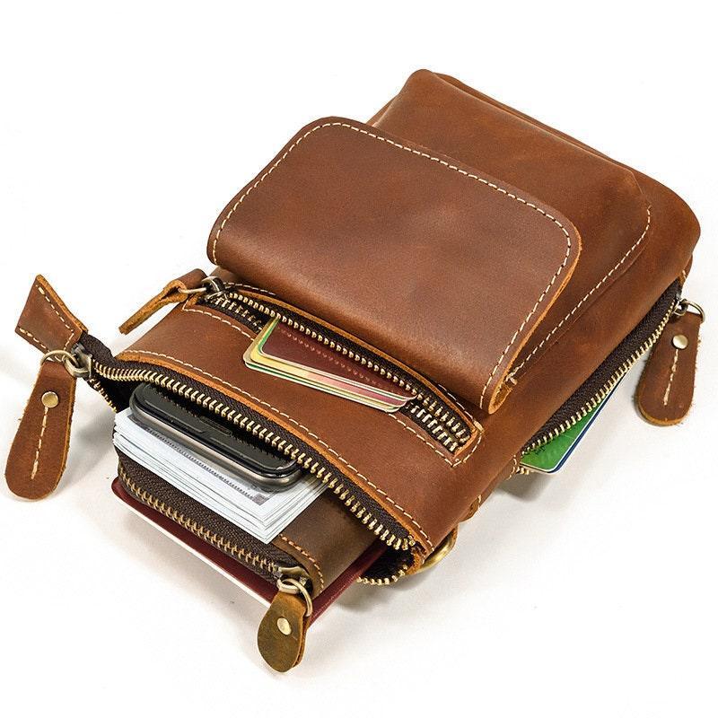 Handcrafted brown full grain leather crossbody belt bag with zippers, holding cards and phone.