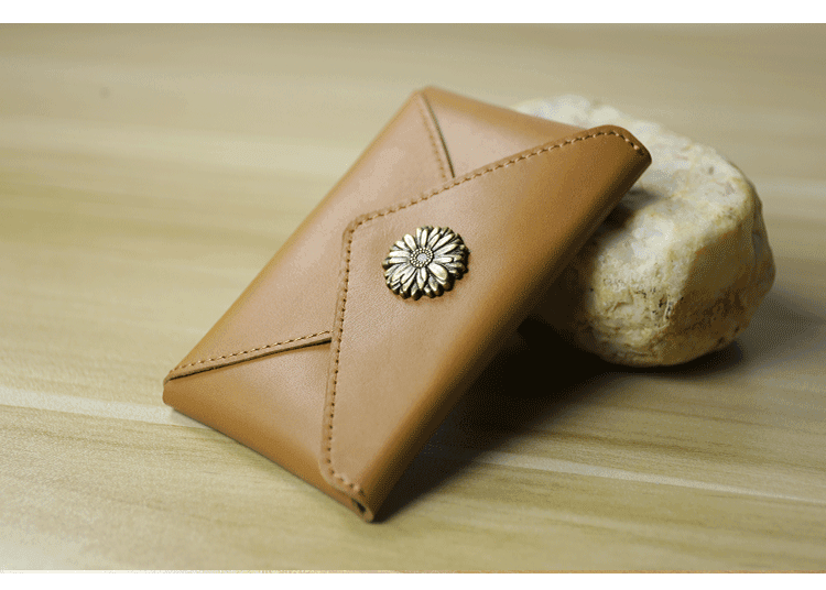 Handcrafted minimalist tan leather slim wallet with floral metal clasp on wooden surface