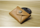 Slim tan leather wallet with floral clasp on wood surface, minimalist coin purse for women