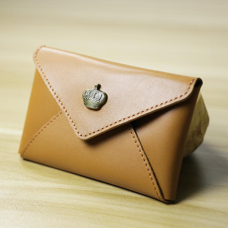 Handcrafted minimalist tan leather slim wallet with crown embellishment on wooden surface