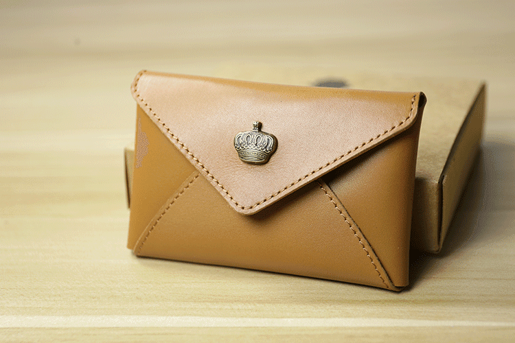 Handcrafted minimalist tan leather slim wallet for women with crown clasp, on wooden desk