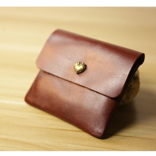 Handcrafted minimalist brown leather slim wallet with gold heart button on wooden surface