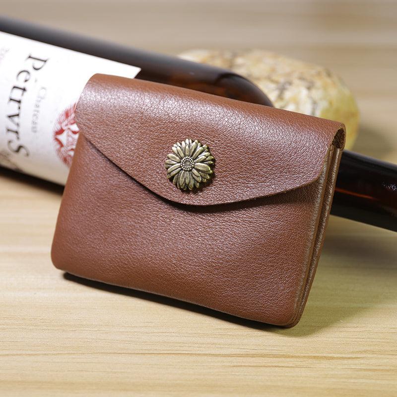 Handcrafted minimalist brown leather slim wallet with floral metal button on wood table