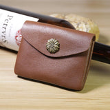 Handcrafted minimalist brown leather slim wallet with floral metal button on wood table