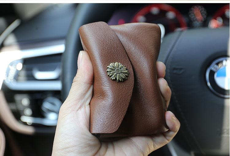 Hand holding a brown handcrafted minimalist leather slim wallet with floral button clasp