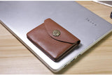 Handcrafted brown leather minimalist slim wallet with floral clasp on a laptop