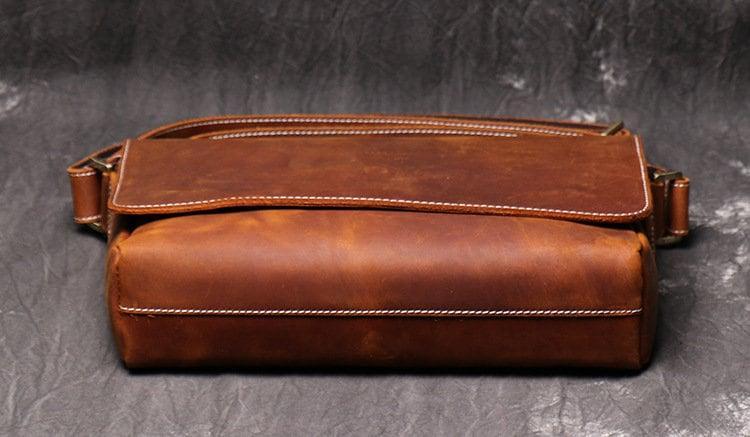 Handcrafted brown cowhide leather shoulder bag with contrast stitching on dark background