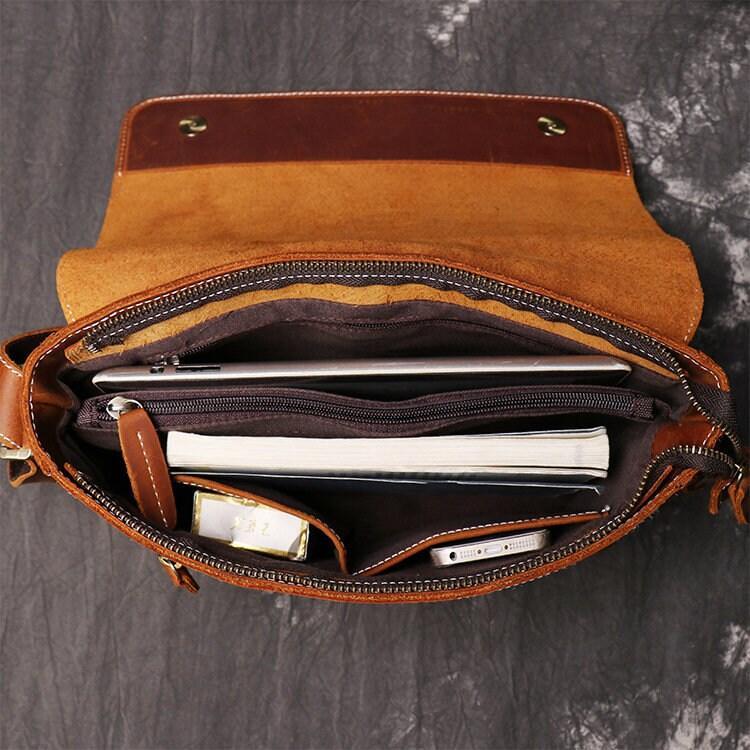 Open handmade cowhide leather shoulder bag with organized compartments, notebook, and phone inside