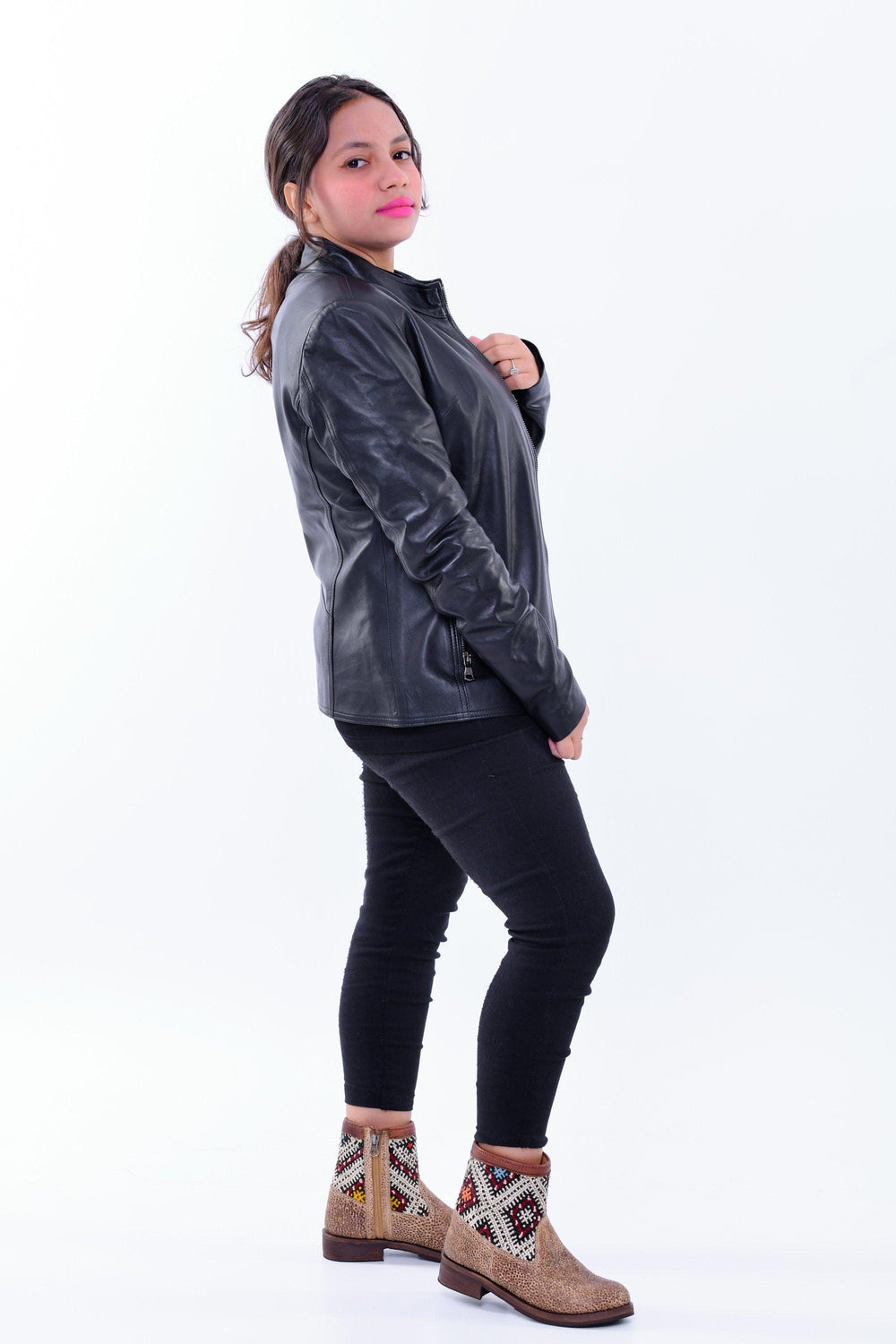 Woman wearing slim fit black genuine leather biker jacket and patterned ankle boots