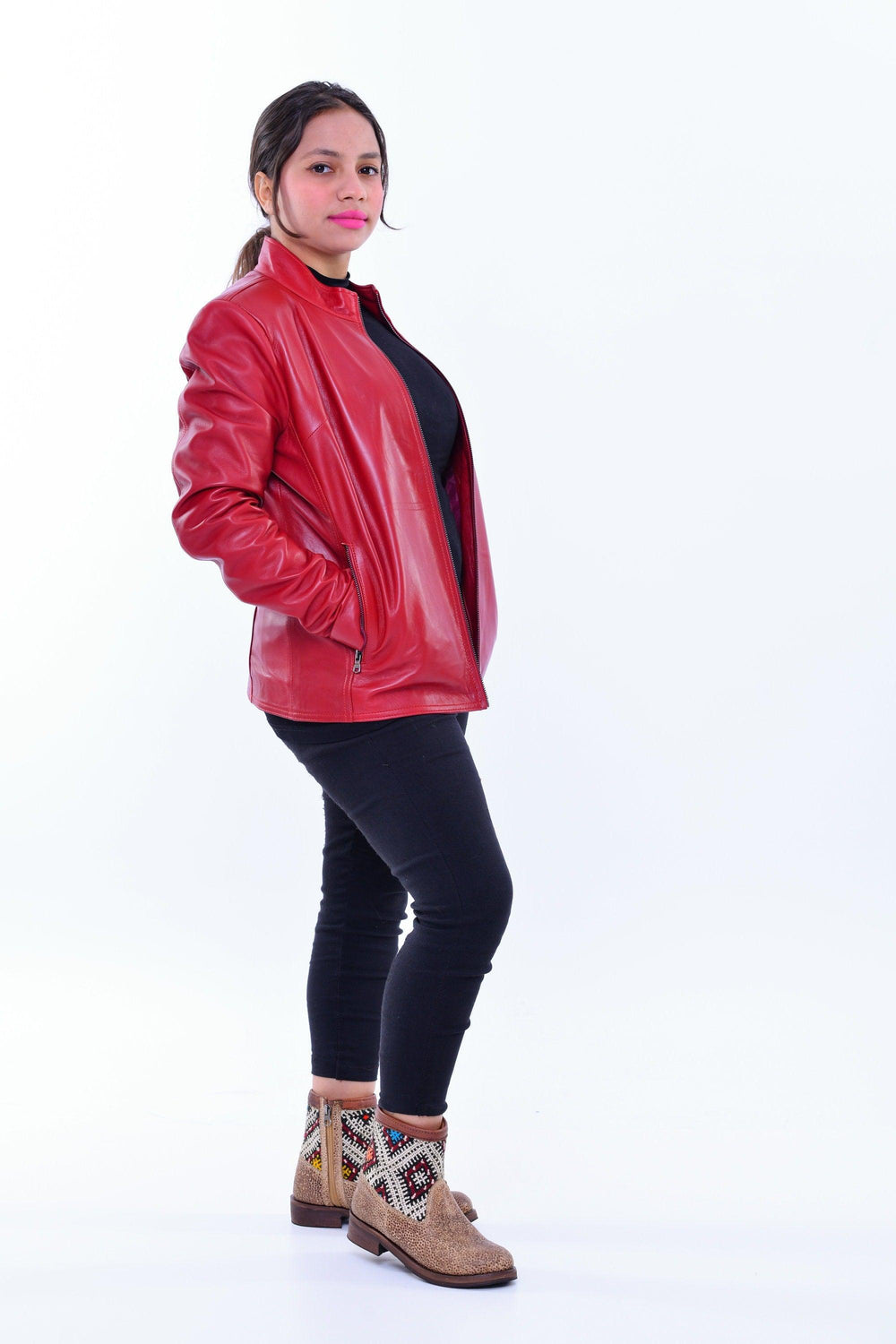 Woman wearing a red genuine leather biker jacket, black pants, and patterned ankle boots
