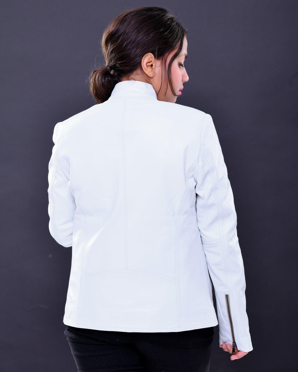 Woman wearing slim fit white genuine leather biker jacket, back view, studio backdrop