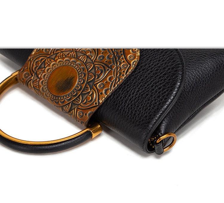 Black leather handbag with embossed floral design and gold metal ring handle