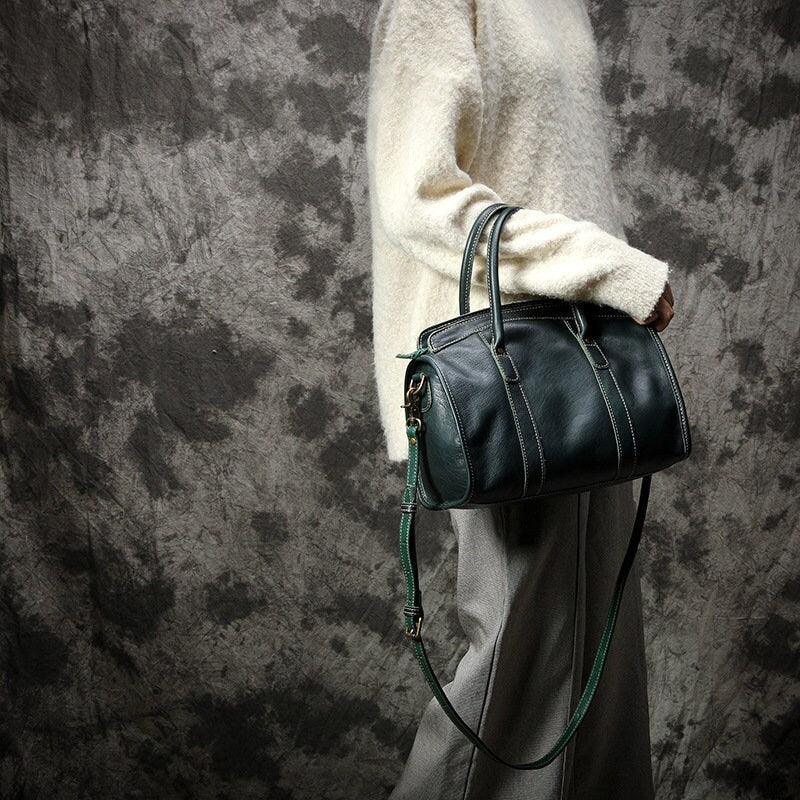 Large black cowhide leather handbag with shoulder strap, showcased by a person in neutral clothing.