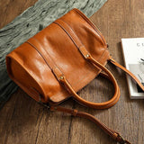 Large brown cowhide leather handbag with double handles on a wooden surface