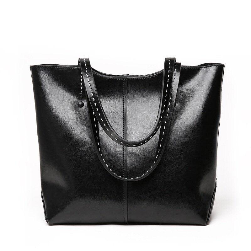 Black leather tote bag with double handles and white stitched trim on plain background