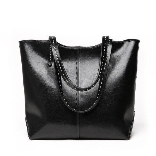 Black leather tote bag with double handles and white stitched trim on plain background
