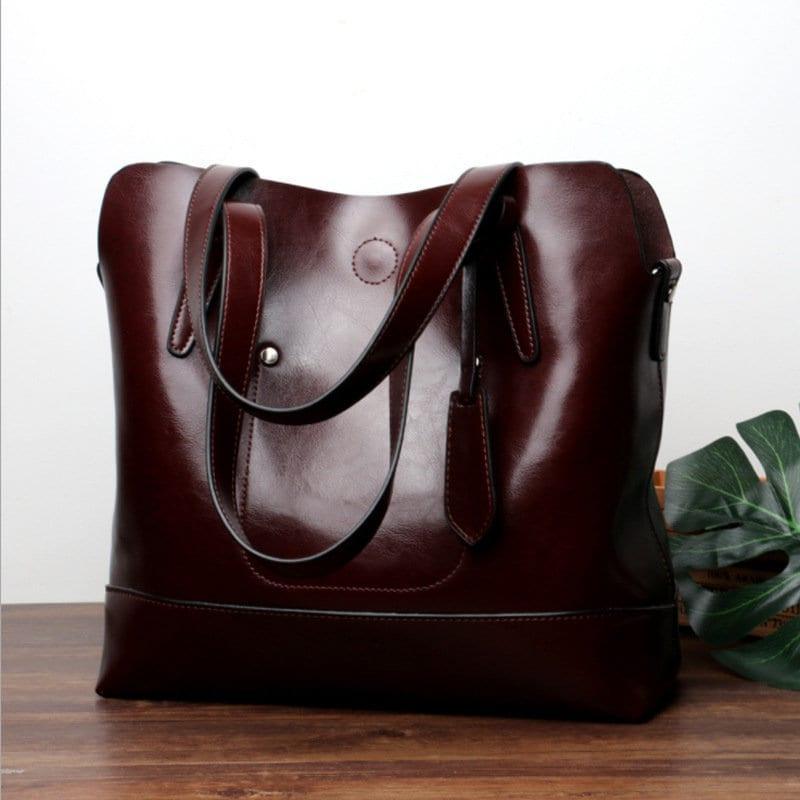 Large brown leather tote shoulder bag with dual handles on wooden surface