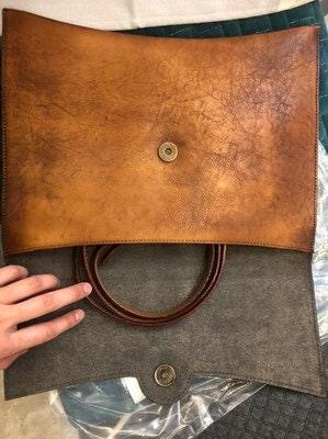 Handcrafted large leather clutch bag open to show brown handles and magnetic closure