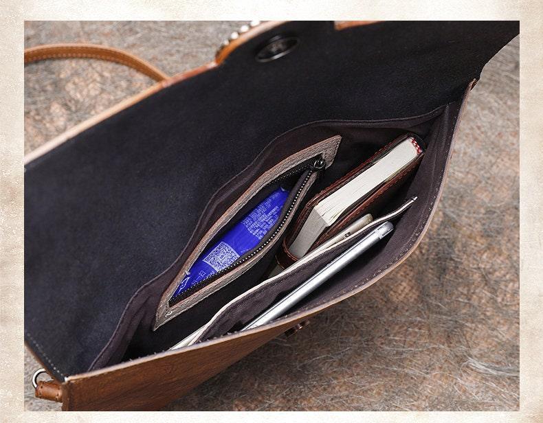 Interior view of large leather clutch bag with compartments holding tablet, book, and accessories
