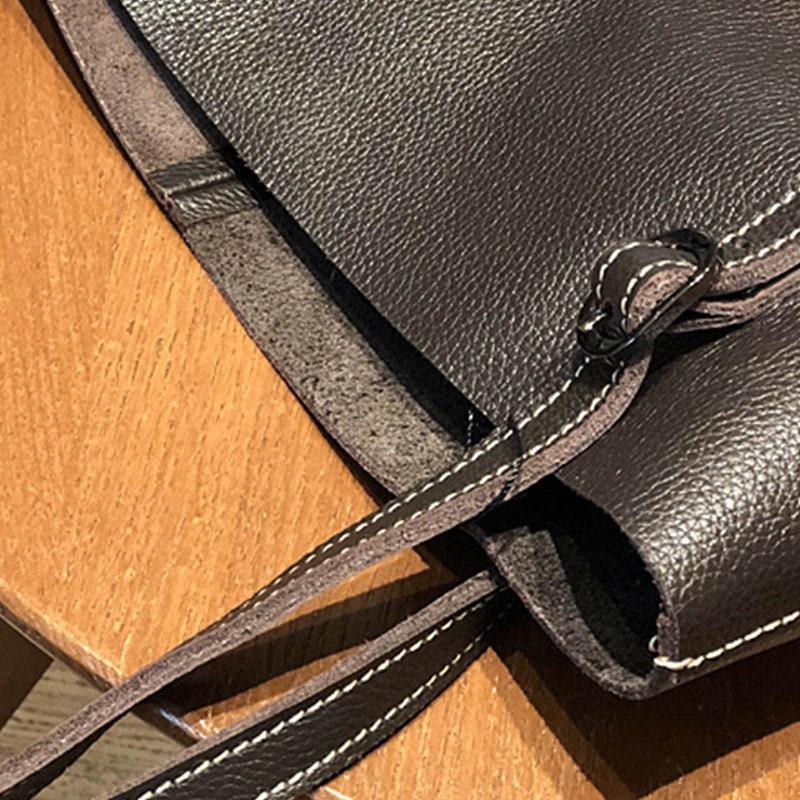 Close-up of large black leather tote bag with white stitching on wooden table