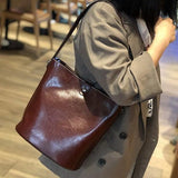 Woman wearing brown leather bucket bag as shoulder bag indoors