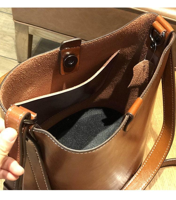 Brown leather bucket bag with shoulder strap, open top and spacious interior pocket