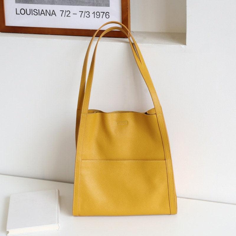Yellow grain cowhide leather tote bag with shoulder straps on a white table