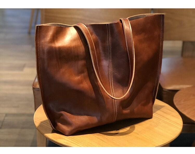 Minimalist large brown leather tote bag with double handles on a wooden chair