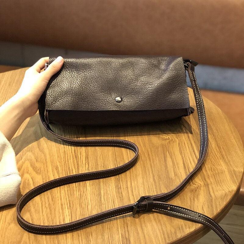 Minimalist small black leather crossbody bag with adjustable strap on wooden table