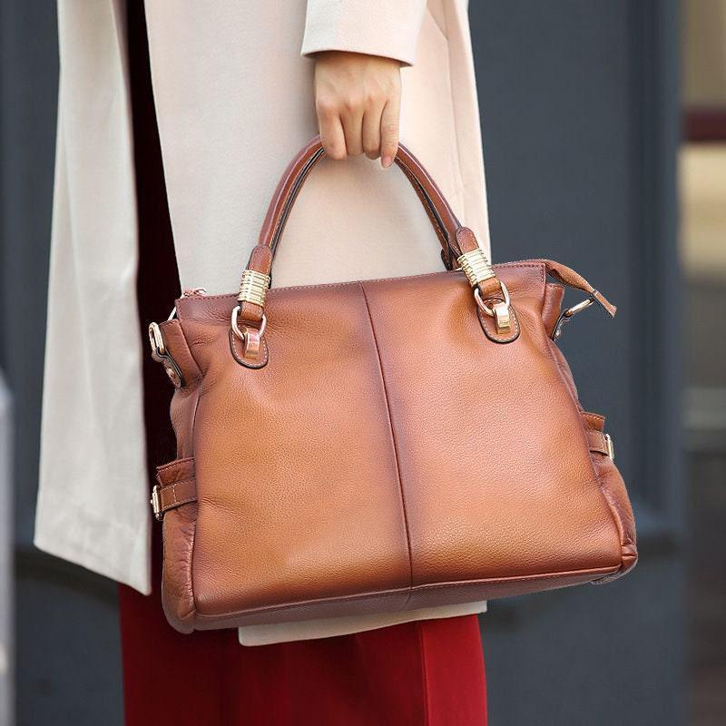 Full-grain leather tote bag in gradient tan, soft and spacious, held by woman in coat