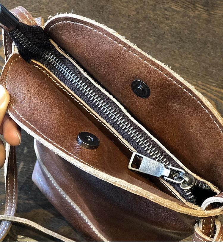 Close-up of small brown genuine leather shoulder bag with zipper and snap closure