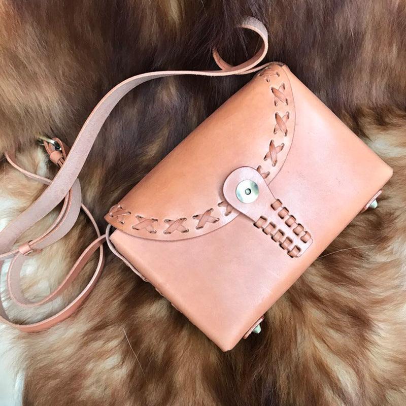 Handcrafted tan leather shoulder bag with stitched detailing and button clasp on fur background