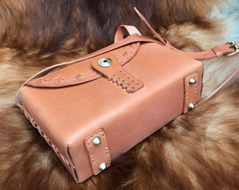 Small handcrafted leather shoulder bag with embossed details and brass hardware on fur background